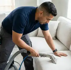 Professional upholstery cleaning technician using an extraction wand to deep-clean a fabric sofa, Fresno, CA.