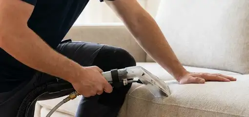 Professional upholstery cleaner deep-cleaning a fabric sofa with a handheld extraction tool, Fresno, CA.